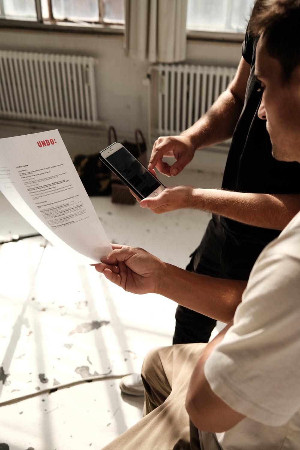 Jonathan Harboe reviews a document while another person shows something on a smartphone.