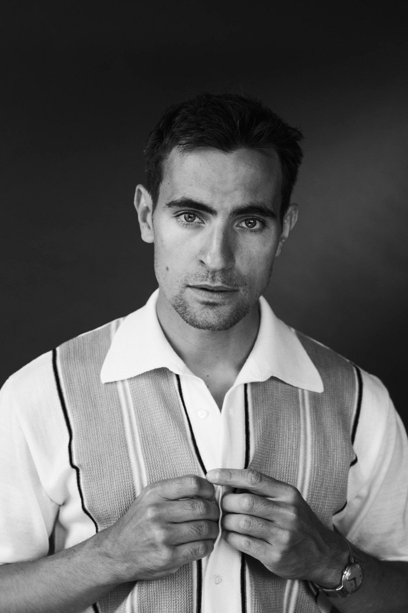 Jonathan Harboe poses in a stylish, vintage-inspired outfit against a dark background.